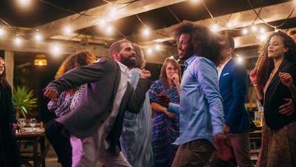 Obraz premium Beautiful Carefree Friends are Dancing Together and Celebrating an Evening Event at a Party. Diverse Multiethnic Young Adult People Have Fun at a Corporate Party in a Restaurant.