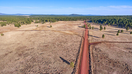 Aerial of large desert plains with red dirt road - obrazy, fototapety, plakaty