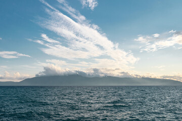 Bright blue ocean in a cloudy blue sky, with islands on the horizon in albania - obrazy, fototapety, plakaty