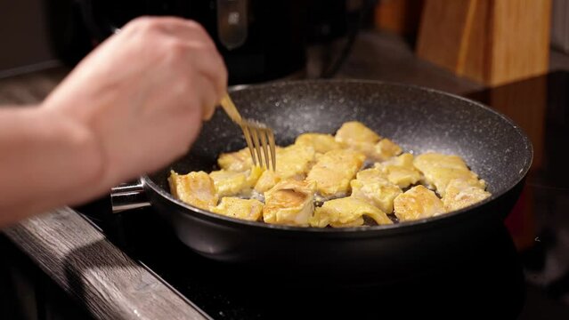 homemade fried fish in batter step by step. step 7 pieces of fish fried in oil in a heated frying pan check and move with a fork in a frying pan