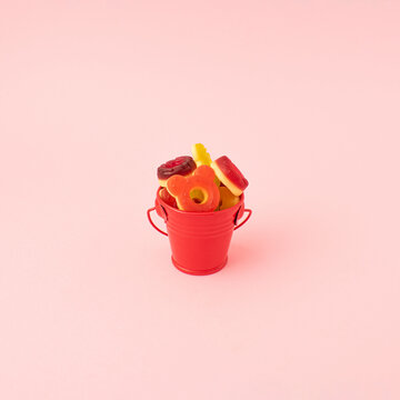 Gammy candies in a shape of dounat in red bucket on pink background. Minimal food concept. Summer party decoration idea.
