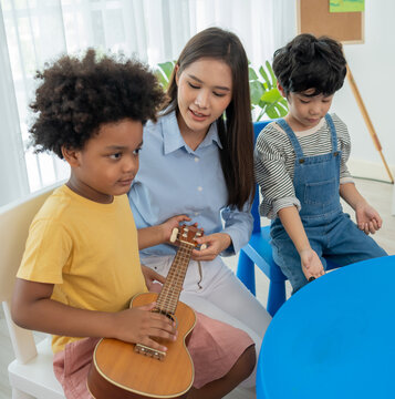 Back to school and summer course. Little children play guitar in kindergarten classroom.