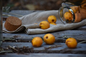 freshly picked orange apricots rolling on wooden board from glass container cork linen cloth