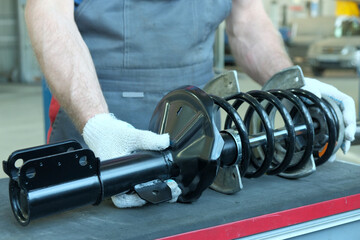 Car service. The suspension of the car. An auto mechanic prepares a new shock absorber rack for...