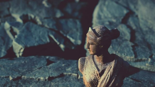 ancient statue of woman on rocky stones
