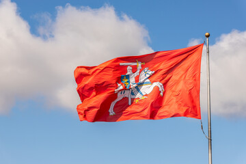 Historical Lithuanian red flag with Vytautas the great figure against sky background. View of waving flag Vytis in Kaunas castle, Lithuania. Red flag with an armour-clad knight on horseback