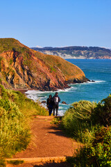 Fototapeta na wymiar Couple on trail leading to beautiful ocean beaches next to hills