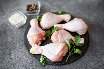 raw chicken legs with spices on a stone background