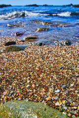 Beach with waves and filled with smooth pieces of colorful glass