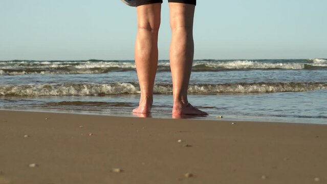 Female legs go into the sea and begin to walk through the water