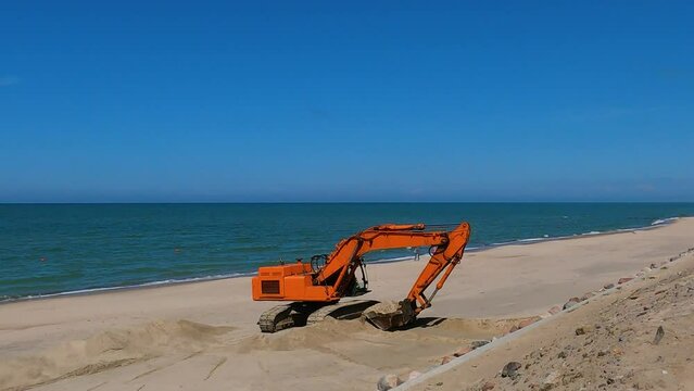 Excavator on the beach, excavator digs sand on the beach