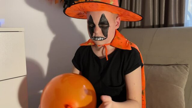 a boy in a Halloween costume inflates balloons on his own, preparing for the Halloween holiday