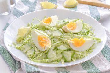 Egg salad with cucumber and cabbage on a white plate. 