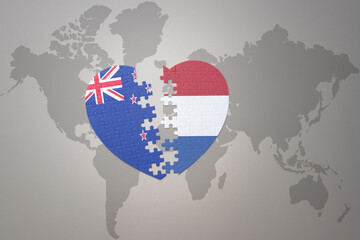 puzzle heart with the national flag of new zealand and netherlands on a world map background. Concept.