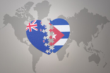 Obraz premium puzzle heart with the national flag of new zealand and cuba on a world map background. Concept.