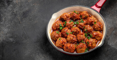 meatballs. Traditional spicy meatballs in sweet and sour tomato sauce in pan on a dark background. Long banner format. top view