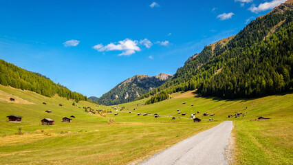 Fototapeta na wymiar Pfundser Tschey is one of the most beautiful high valleys of Tyrol (Austria). The panorama with hay barns and the Maria Schnee chapel is gorgeous. Tschey means high valley in Rhaeo-Romanic.