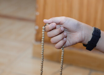 Beautiful boy hands praying with the rosary. A hand holding prayer beads isolated over wood background.