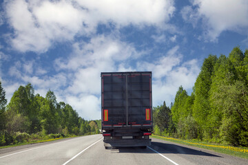 The truck is moving along a suburban highway. Cargo transportation, logistics.