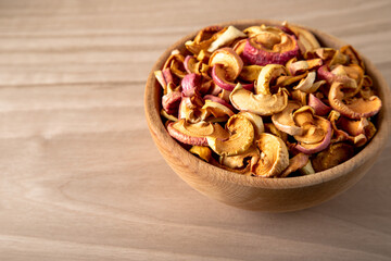Bowl full of dried apples on a wooden background