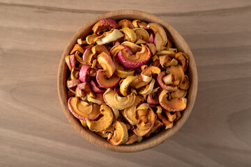 Bowl full of dried apples on a wooden background