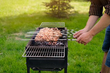 A man is frying a meat kebab in the garden in nature. A weekend in the fresh air. Grill for frying...