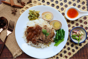 Stewed Pork leg and egg over rice at top view on wood table - Thai - Chinese food called Khao Kha Moo