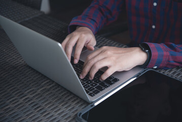 Man hands typing on laptop computer keyboard on table, working at coffee shop, close up