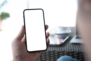 Cell phone blank white screen mockup. Man hands holding, using mobile phone at coffee shop, template for advertisement
