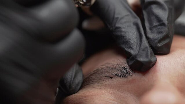 Extreme close-up of micro blading procedure on a man's eyebrow