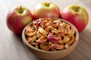 Dried apple slices and fresh apples on wooden background