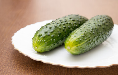 two green cucumbers lie on a white plate