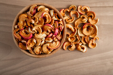 Bowl full of dried apples on a wooden background