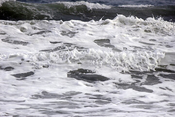 Close-up of the white froth from small waves gently breaking on the surface of the ocean