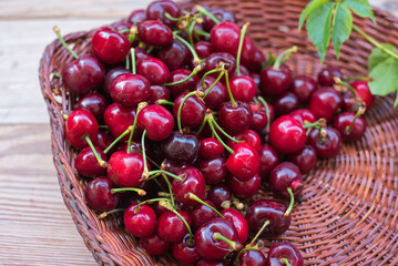 Ripe red cherries in a bowl and next to it on wooden table