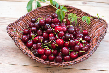 Fototapeta na wymiar Ripe red cherries in a bowl and next to it on wooden table