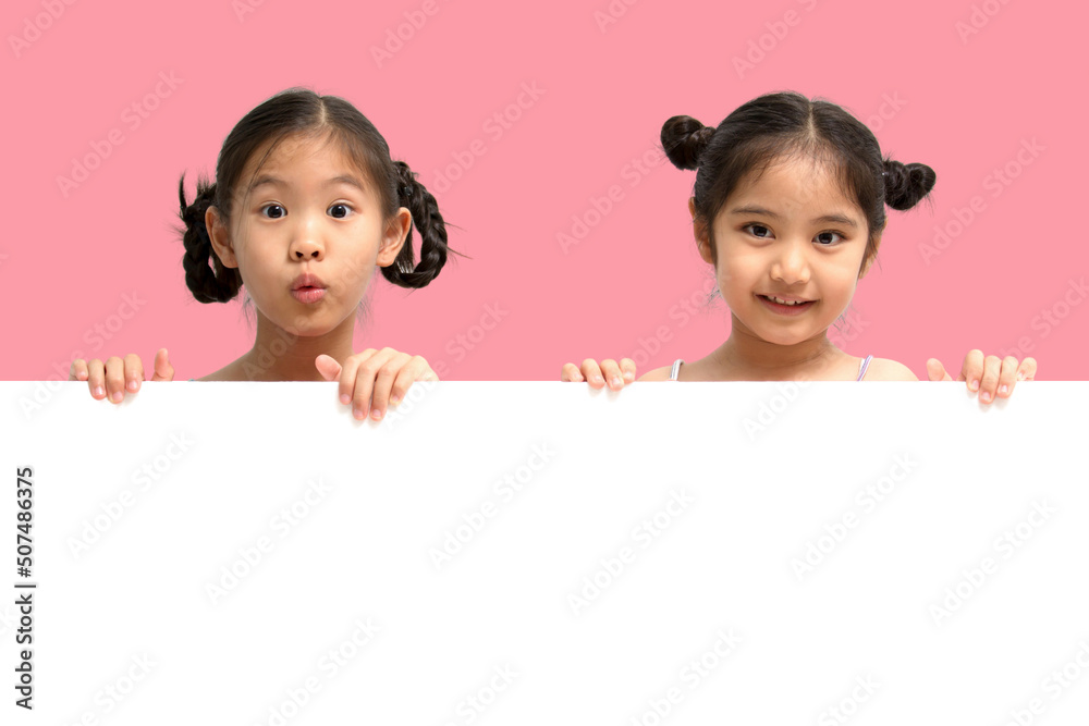 Wall mural happy little asian child girl smiling and showing white blank sign billboard isolated on pink backgr