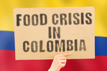 The phrase " Food crisis in Colombia " is on a banner in men's hands with a blurred Colombian flag in the background. Crisis. Finance. Life. Nutrition. Bread. Disaster. Collapse. Social issue