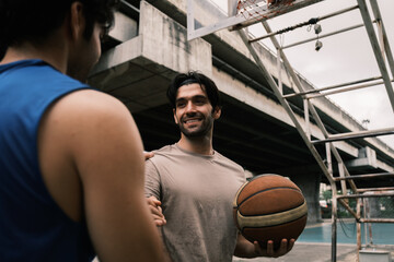 Two caucasian men pratice baskegball in court at urban street.