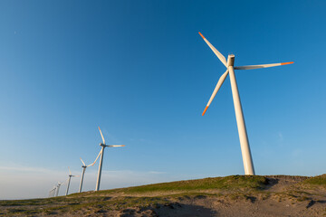 青空と海岸の風力発電の風車。茨城県神栖市須田浜海岸の波崎ウインドファーム。