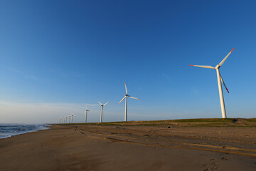青空と海岸の風力発電の風車。茨城県神栖市須田浜海岸の波崎ウインドファーム。