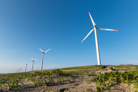 青空と海岸の風力発電の風車。茨城県神栖市須田浜海岸の波崎ウインドファーム。