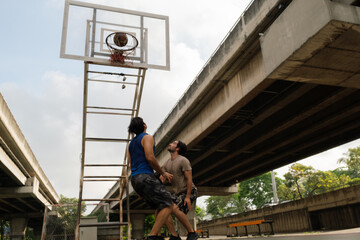 Two caucasian men pratice baskegball in court at urban street.