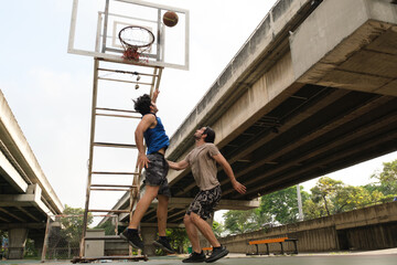 Two caucasian men pratice baskegball in court at urban street.