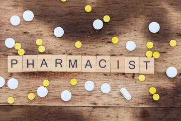 wooden block with the word pharmacist written on it with a wooden backdrop and medicine