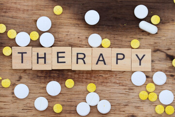 Obraz premium wooden block with the word therapy written on it with a wooden backdrop and medicine