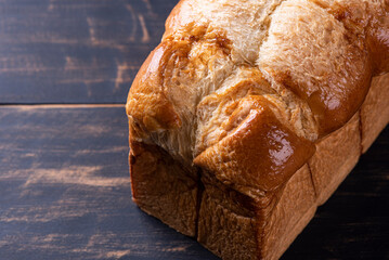 Brioche bun seen close up on plain wooden background. Space for text. Top view.