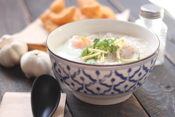 Congee in a Thai-patterned cup and fried batter served in an Asian-style cup on a black table with fried batter that we call 