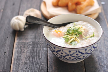 Congee in a Thai-patterned cup and fried batter served in an Asian-style cup on a black table with fried batter that we call 