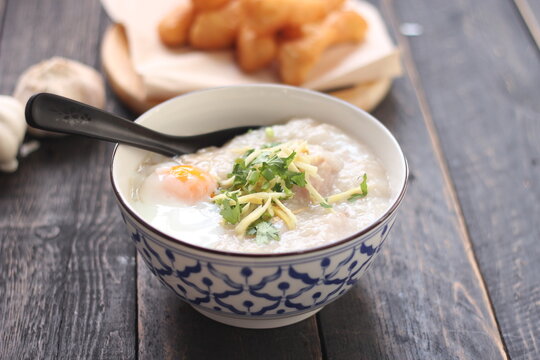 Congee in a Thai-patterned cup and fried batter served in an Asian-style cup on a black table with fried batter that we call "Patongo".